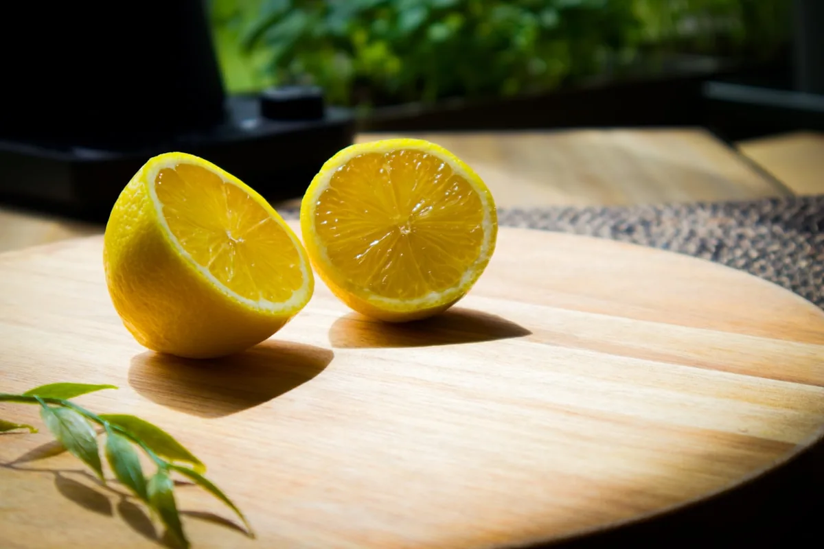 Halved fresh lemons on a wooden cutting board in warm sunlight
